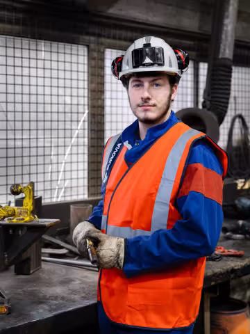 Ouvrier équipé d’un casque et d’un gilet de sécurité dans un atelier industriel.